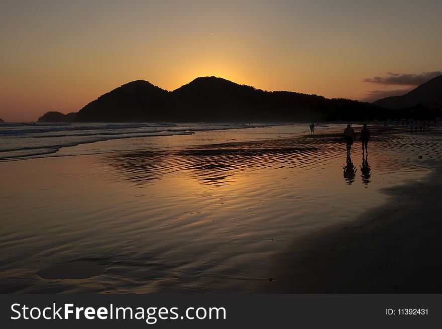 Sunset at the Baleia Beach in Brazil, with golden reflexion from the sun in the ocean and people enjoying the end of the afternoon. Sunset at the Baleia Beach in Brazil, with golden reflexion from the sun in the ocean and people enjoying the end of the afternoon