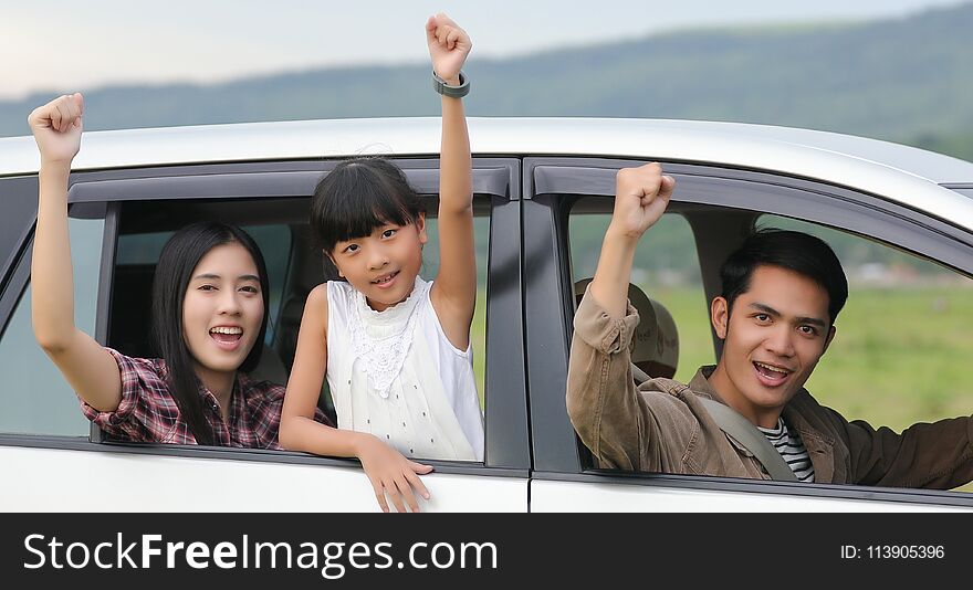 Happy little girl with asian family sitting in the car for enjoying road trip and summer vacation in camper van