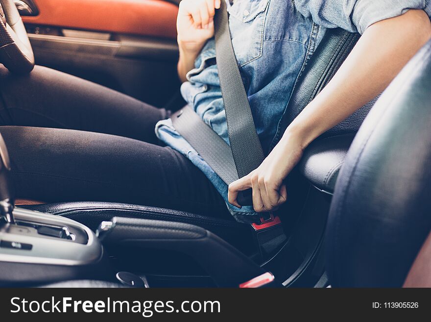 Asian woman fastening seat belt in the car, safety concept.