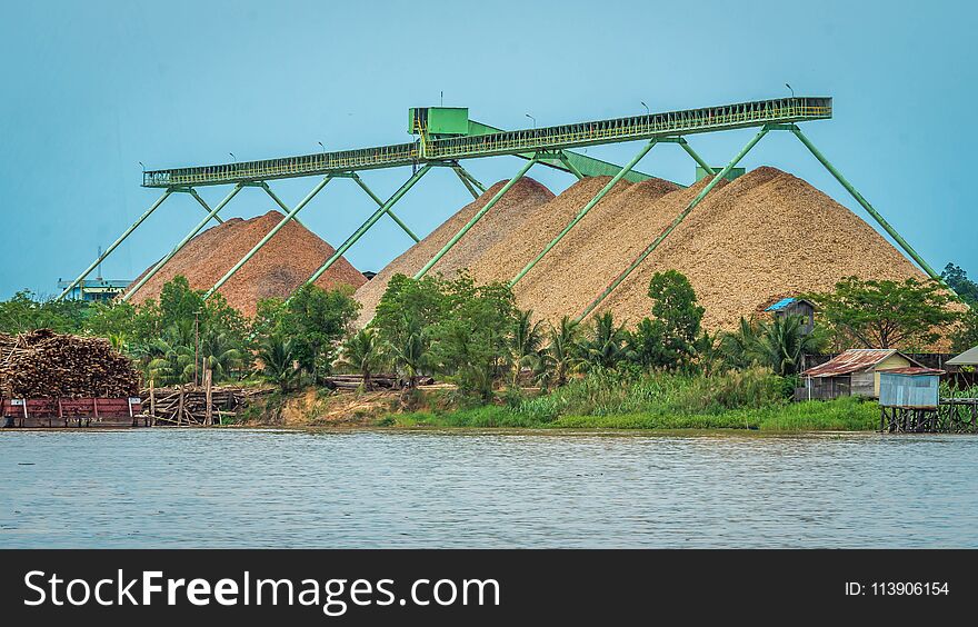 Wood chip stockpile factory on Mahakam riverbank. industrial background
