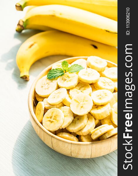 Raw yellow banana fruit slices in wooden bowl