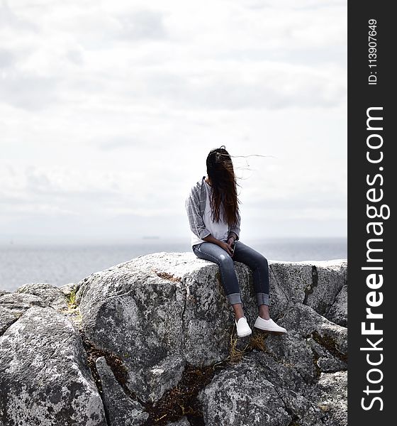 Woman Sits on Gray Rock
