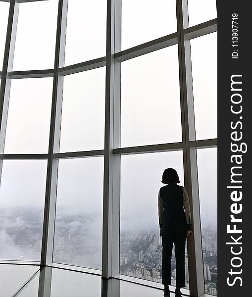 Woman Standing in Front of Glass Panel Inside Building