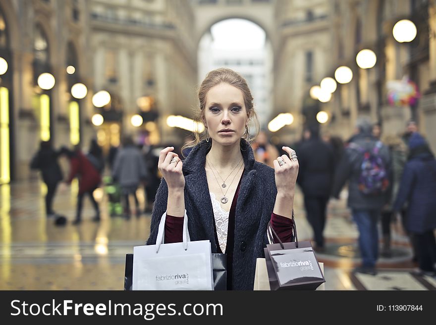 Woman Wearing Black Coat Holding Assorted-color Shopping Bags on Building