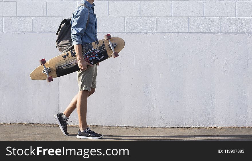 Man In Blue Top Carrying A Longboard