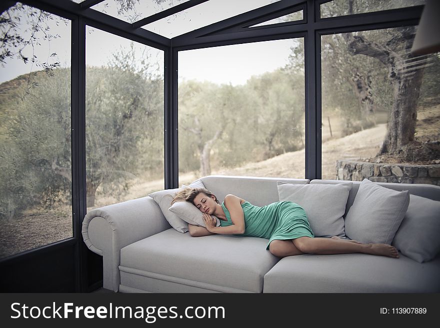 Woman Sleeping On Sofa With Throw Pillows
