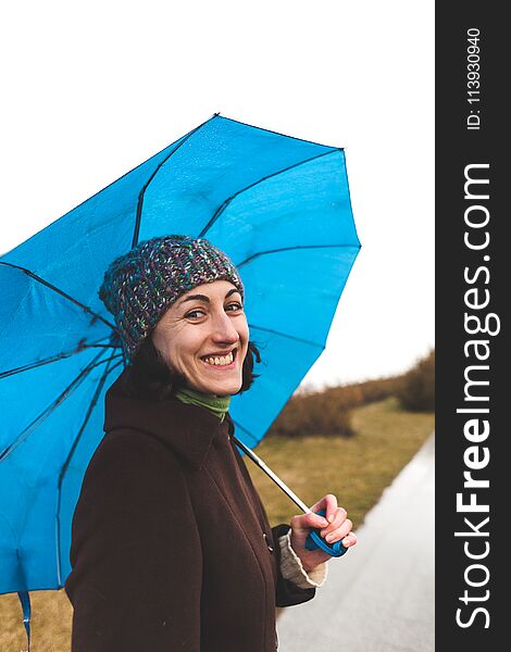 Portrait of a woman in a coat and a knitted hat. Walk on a rainy autumn day. Smiling girl with an umbrella. Portrait of a woman in a coat and a knitted hat. Walk on a rainy autumn day. Smiling girl with an umbrella.