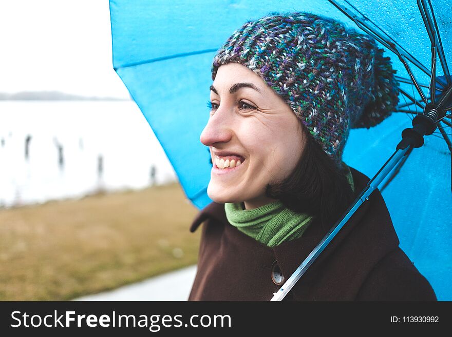Portrait of a woman in a coat and a knitted hat. Walk on a rainy autumn day. Smiling girl with an umbrella. Portrait of a woman in a coat and a knitted hat. Walk on a rainy autumn day. Smiling girl with an umbrella.