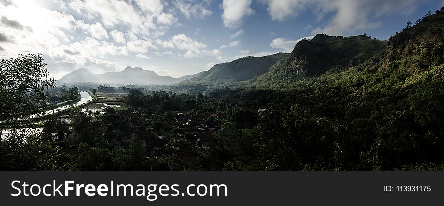 Panoramic green valley and the village in the spring morning. the landscape beyond the river village and mountains