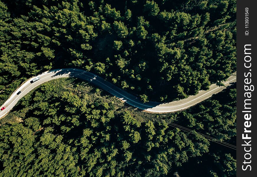 Aerial view from drone of curve road on the mountain with green forest in Greece