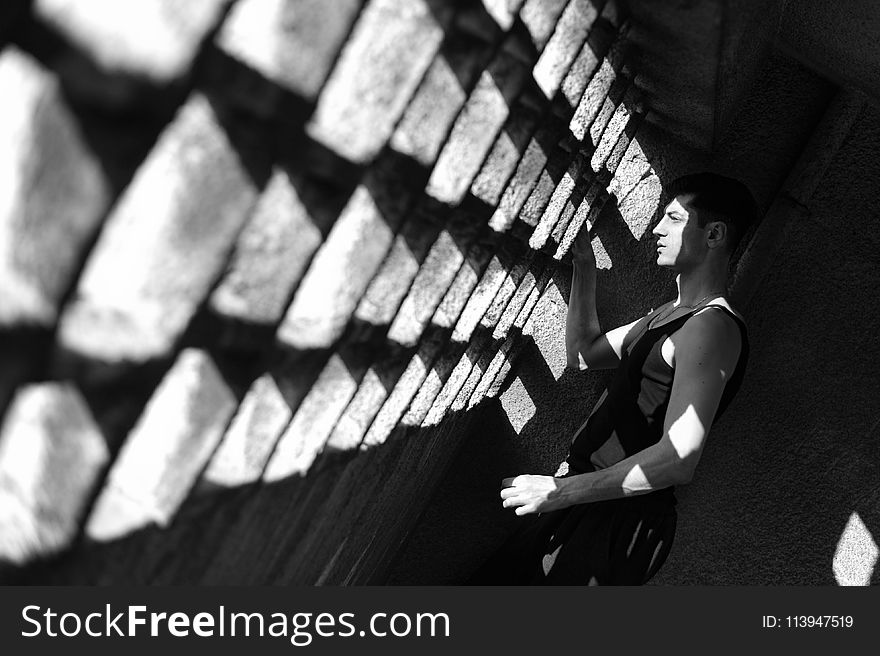 Grayscale Photo of Man Wearing Tank Top Staring at Window