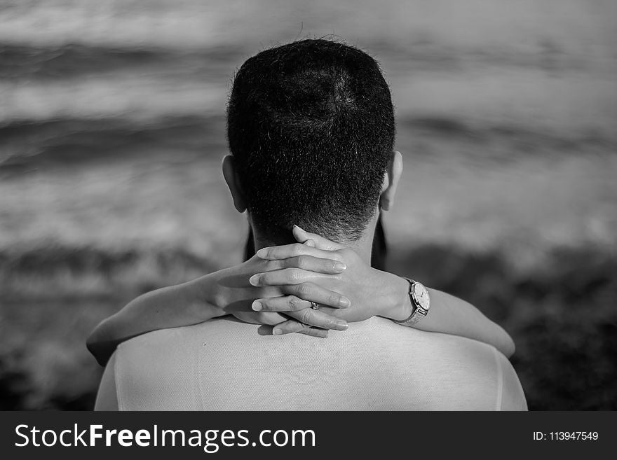 Grayscale Photo of Man Hugged by Woman