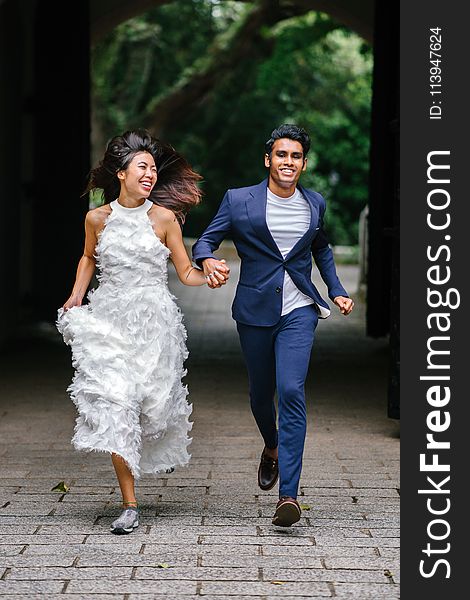 Bride and Groom Running on Concrete Pathway