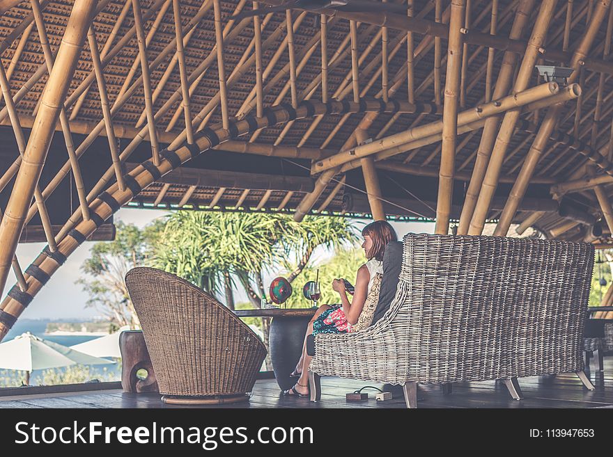 Woman Sitting On Brown Wicker Chair