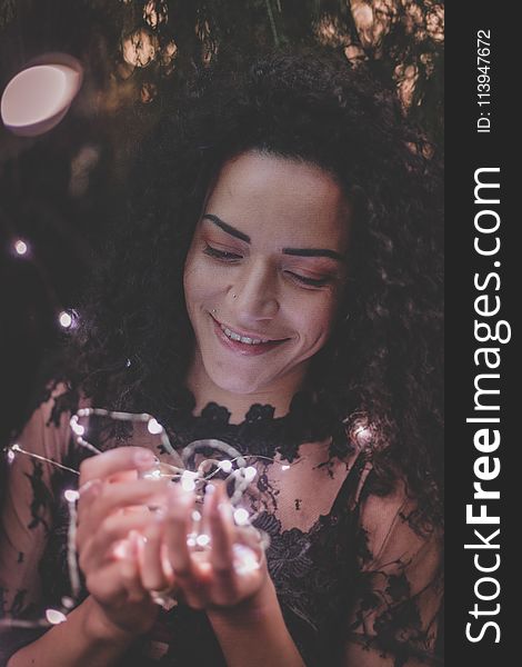 Woman Holding String Lights While Smiling