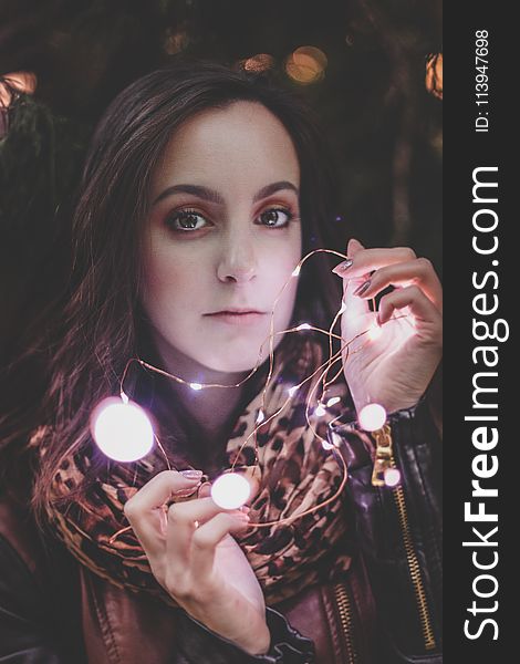 Woman Wearing Leather Jacket And Leopard Print Scarf Holding String Light