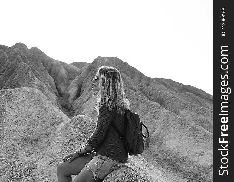 Grayscale Photo of Woman Sitting on Rock