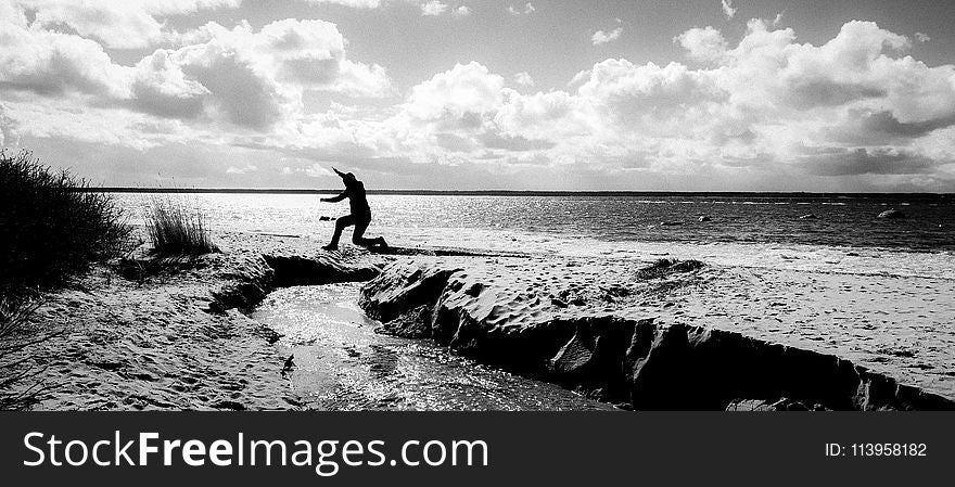 Grayscale Photography of a Person Jumping over Body of Water