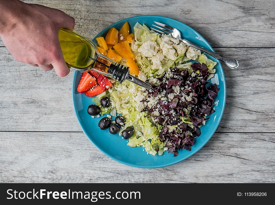 Person Pouring Vegetable Oil on Vegetable Salad