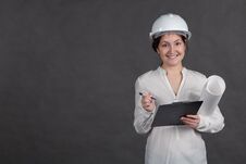 Young Female Architect In A Protective Helmet Makes Notes On The Project With A Paper In Hands Royalty Free Stock Image