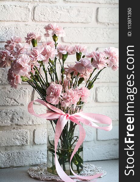 Pink carnations on white windowsill. White brick wall