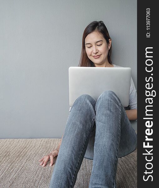 Closeup Asian Woman Sitting For Use Computer Notebook In Work Concept On Blurred Cement Wall Textured Background With Copy Space