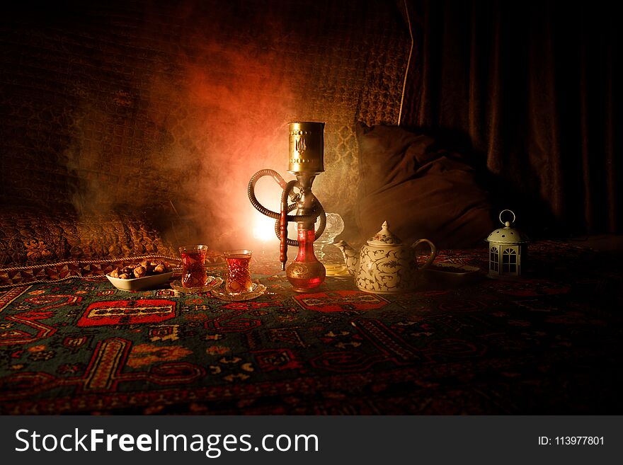 Hookah hot coals on shisha bowl making clouds of steam at Arabian interior. Oriental ornament on the carpet eastern tea ceremony.