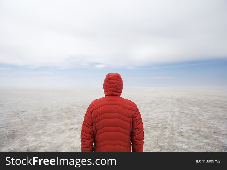 Young man in winter hooded jacket at Salar de uyuni salt flat in Bolivia