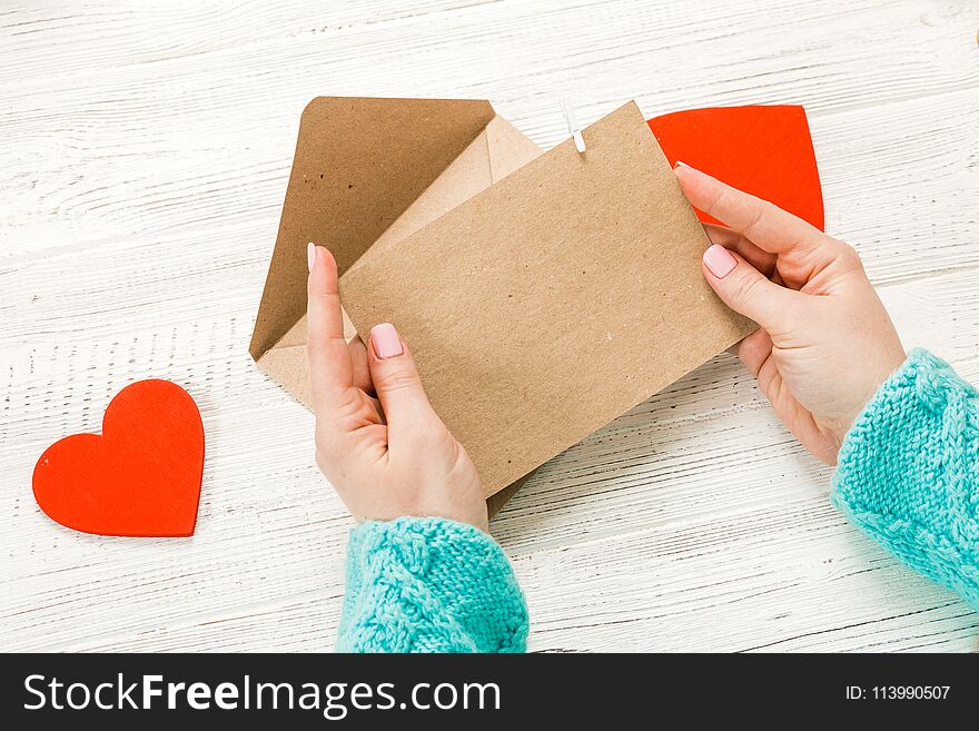 Hand of girl writing love letter on Saint Valentines Day. Handmade postcard with red heart shaped figure. 14 February holiday celebration. Valentine day concept with copy space.