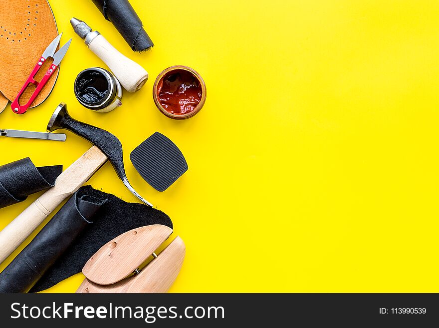 Clobber tools. Hummer, awl, knife, sciccors, wooden shoe, paint and leather. Yellow background top view space for text