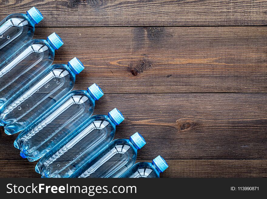 Drinking water in bottles on dark wooden background top view copy space