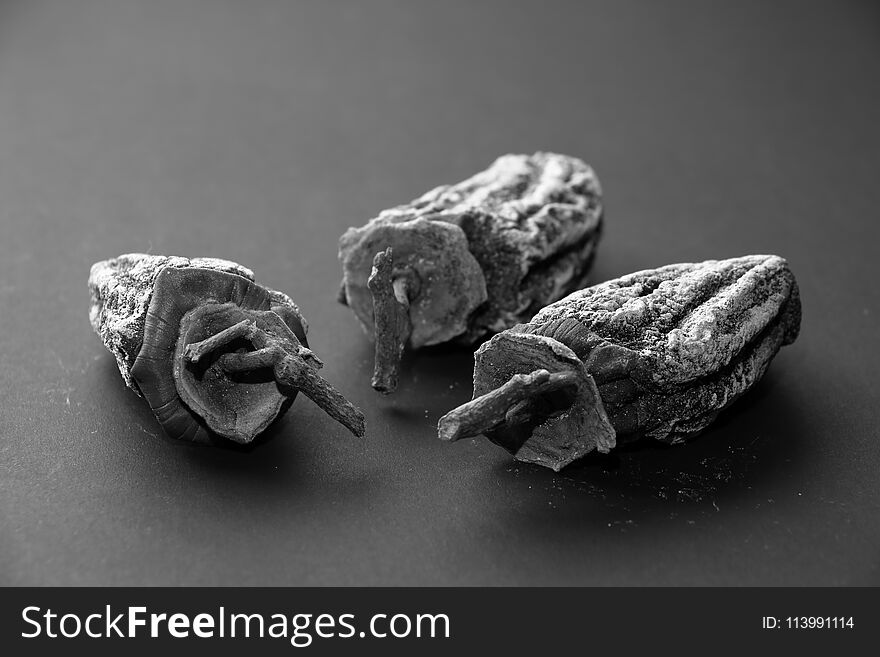 Three dried persimmons on a dark background