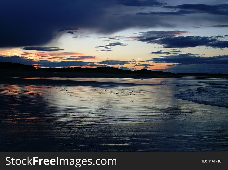 Sunset over a deserted beach with clouds coming in. Sunset over a deserted beach with clouds coming in