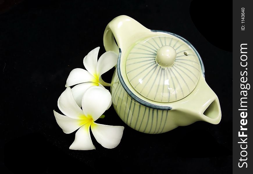 A photo of teapot and plumeria flower. A photo of teapot and plumeria flower