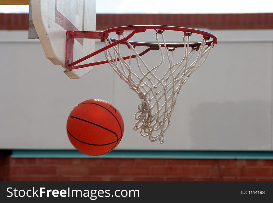 A basketball going through the hoop and net. A basketball going through the hoop and net.