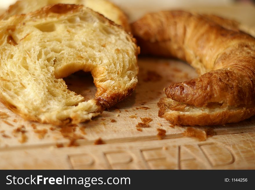Sliced croissants on a chopping board with crumbs. Sliced croissants on a chopping board with crumbs