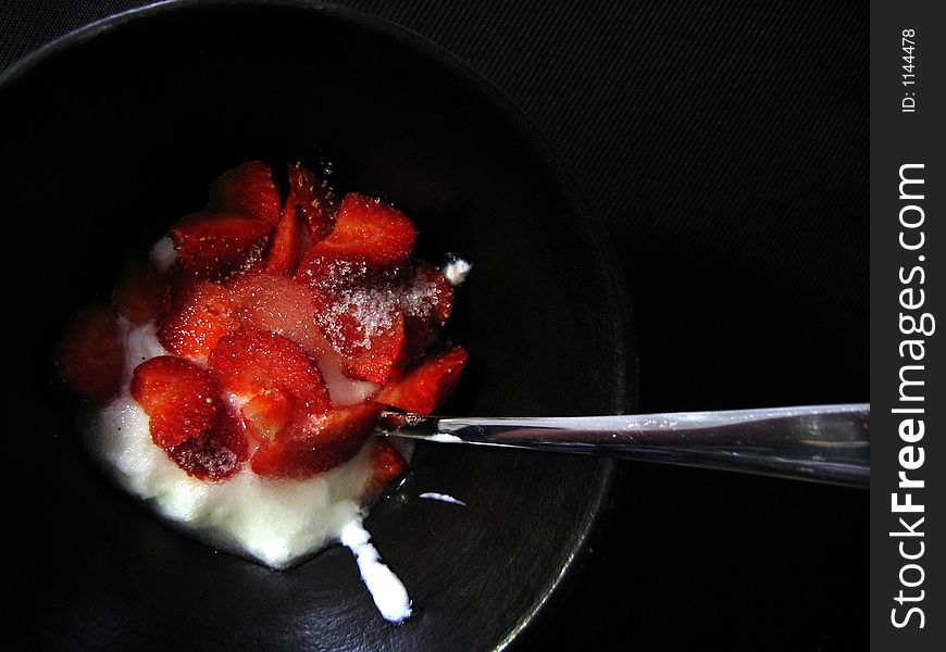 Strawberries with sugar and yoghurt in a plate on black background. Strawberries with sugar and yoghurt in a plate on black background.
