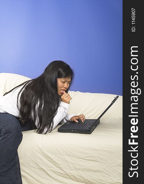 Girl typing on laptop on white couch. Girl typing on laptop on white couch