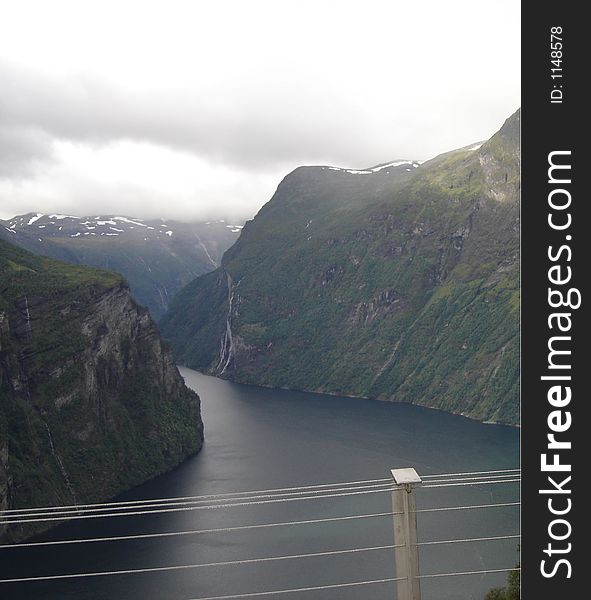 Stream flowing between two mountains in Norway...where the mountains seem to reach the clouds in the distance. Stream flowing between two mountains in Norway...where the mountains seem to reach the clouds in the distance