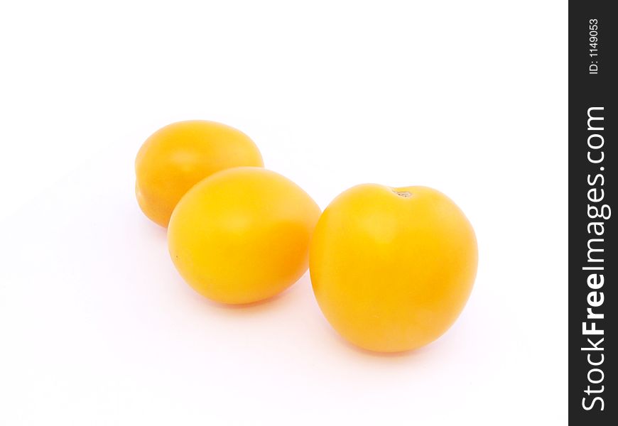 Three yellow tomatoes on the white