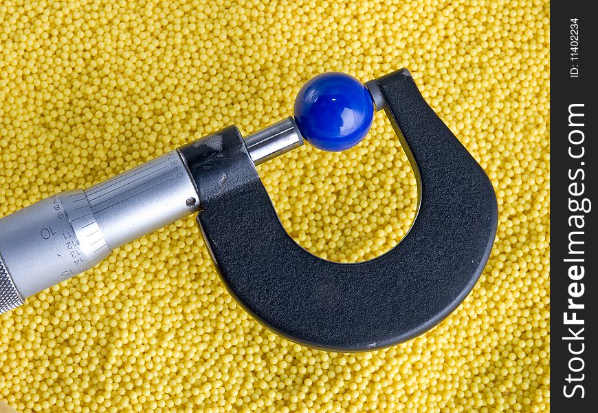 Micrometer with Beads and Balls. Plastic colorful beads and a micrometer measuring a plastic ball