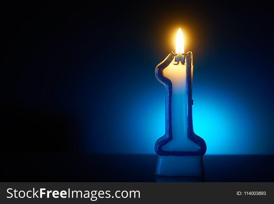 Number One - Burning birthday candle on blue background