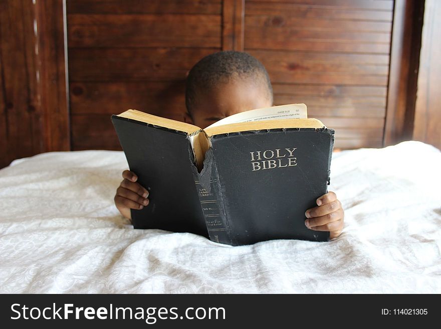 Photo of Child Reading Holy Bible