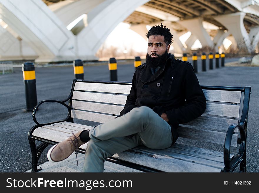 Man in Black Jacket Sitting on Outdoor Bench