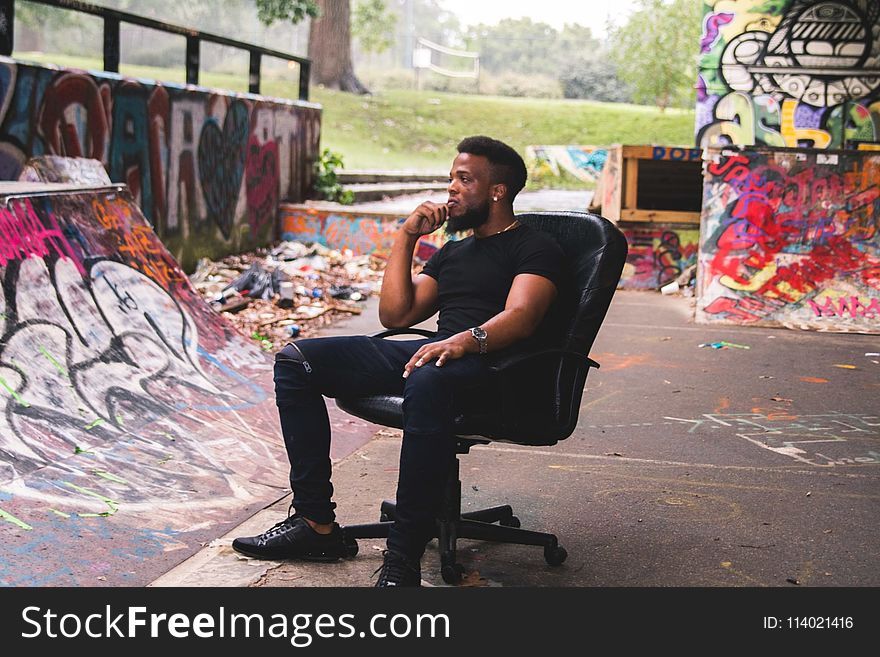 Man Wearing Black Crew-neck Shirt Sitting on Leather Rolling Chair