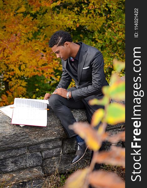 Man Wearing Black Suit Reading Book