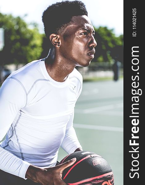 Man In White Crew-neck Long-sleeved Shirt Holding Black And Red Basketball