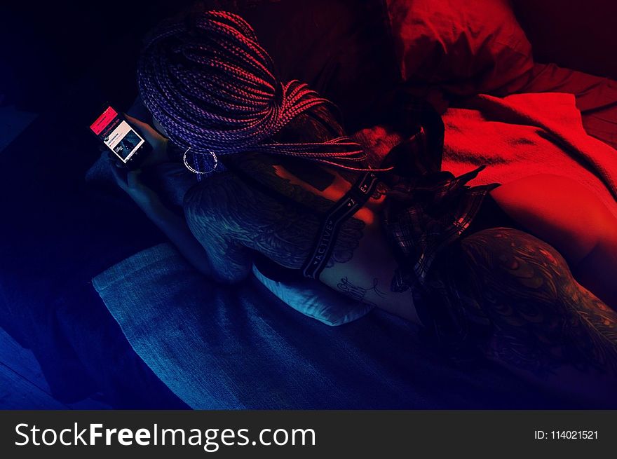 Woman on her back Laying in Bed Holding Phone