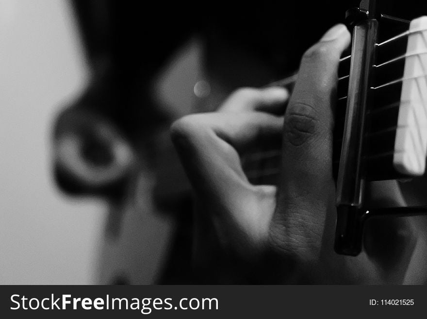 Person Holding Guitar In Grayscale Photography