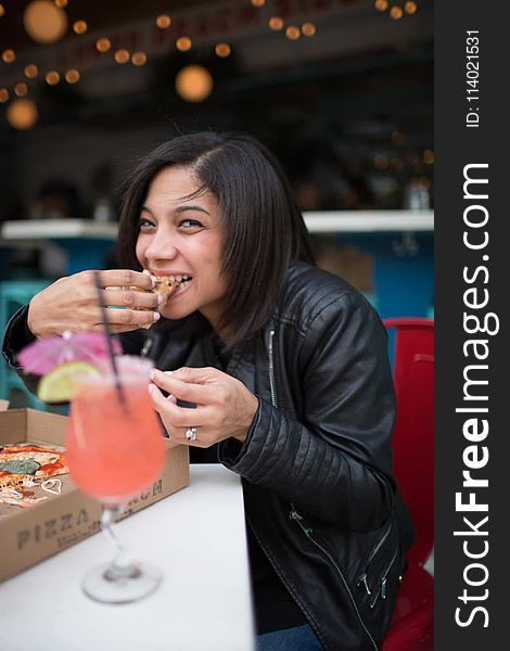 Woman Wearing Black Leather Jacket Eating Pizza